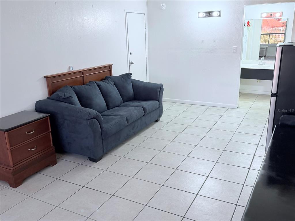 A room with white tile floors, a dark blue sofa, and an adjacent bathroom vanity — 43420 HIGHWAY 27 UNIT 436, DAVENPORT, FL