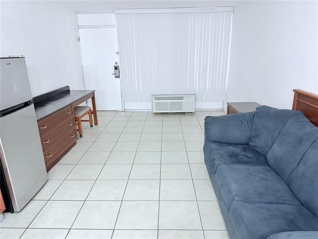 A studio apartment features a blue sofa, a small kitchenette area, and white tile flooring — 43420 HIGHWAY 27 UNIT 436, DAVENPORT, FL