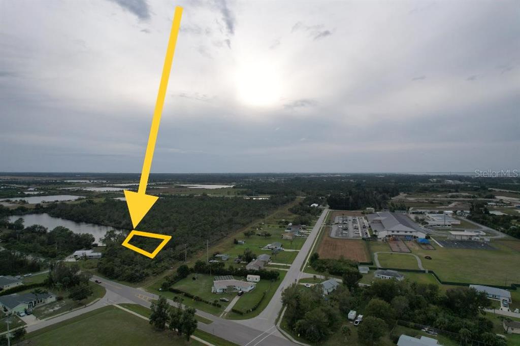 An aerial view shows a vacant lot highlighted by a yellow arrow near a lake — 4515 S FAIRWAY DRIVE, PUNTA GORDA, FL