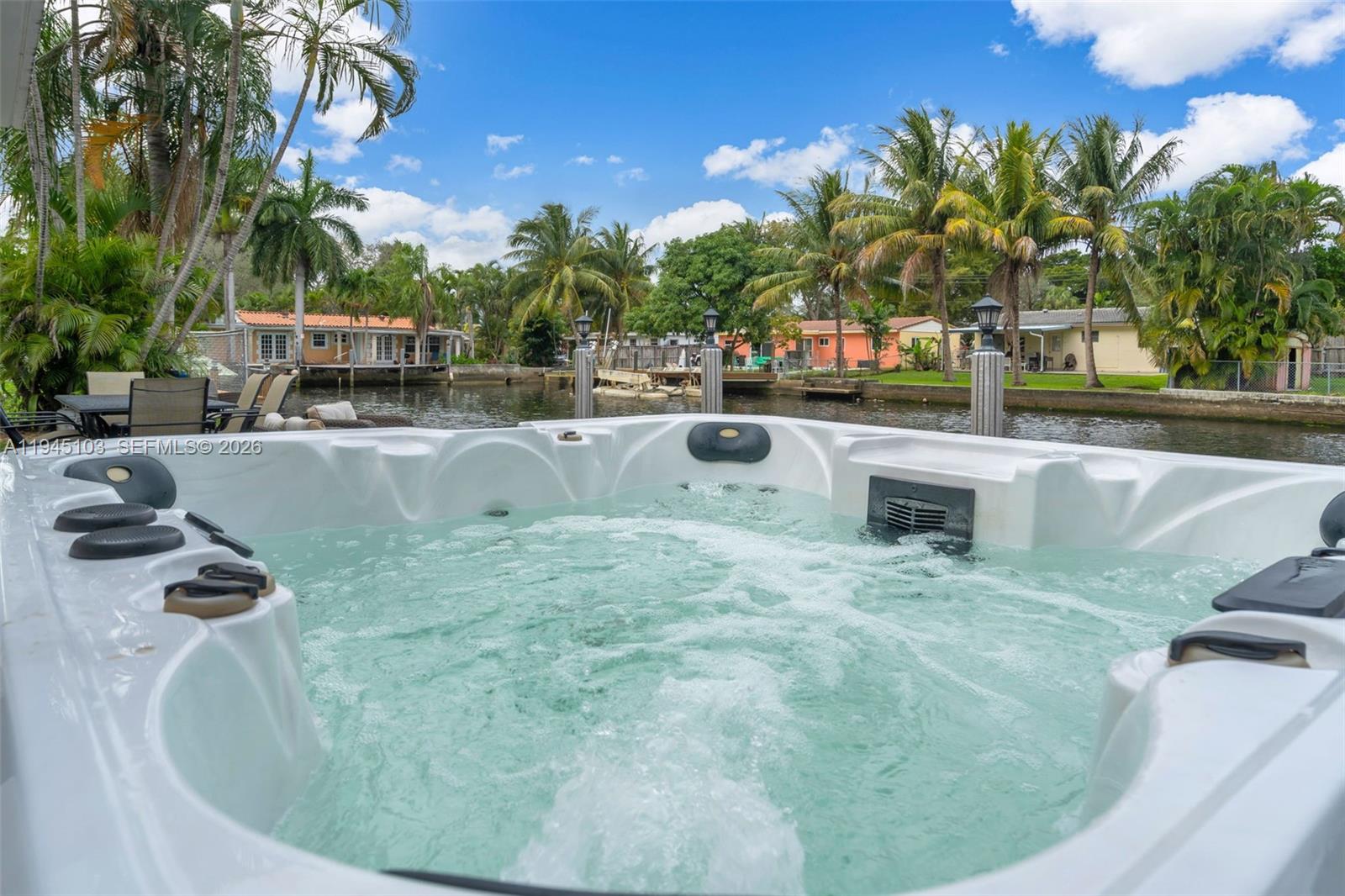 A white hot tub sits on a deck overlooking a canal with palm trees — 2721 Harding St, Hollywood FL 33020, HOLLYWOOD, FL