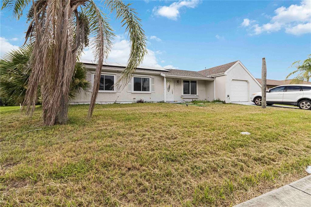 A single-story house with a light-colored exterior, a garage, and a front yard with palms — 20550 EDGEWATER DRIVE, PORT CHARLOTTE, FL