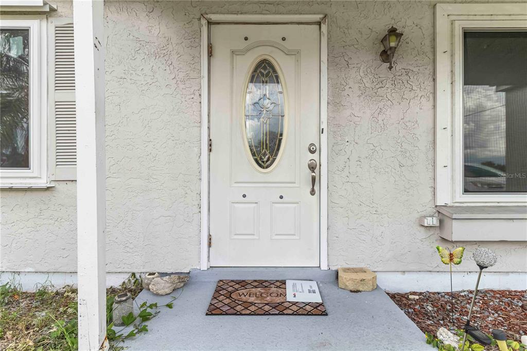 A white front door with an oval glass insert sits on a concrete porch — 20550 EDGEWATER DRIVE, PORT CHARLOTTE, FL