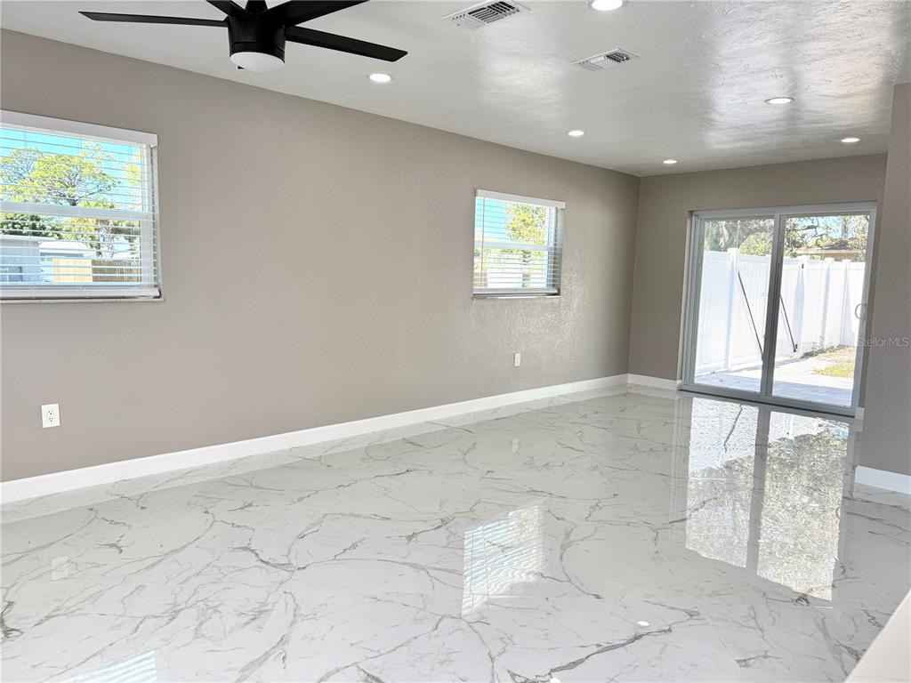 A living room with light gray walls, recessed lighting, and white marble-patterned tile flooring — 715 65TH AVENUE DRIVE W, BRADENTON, FL