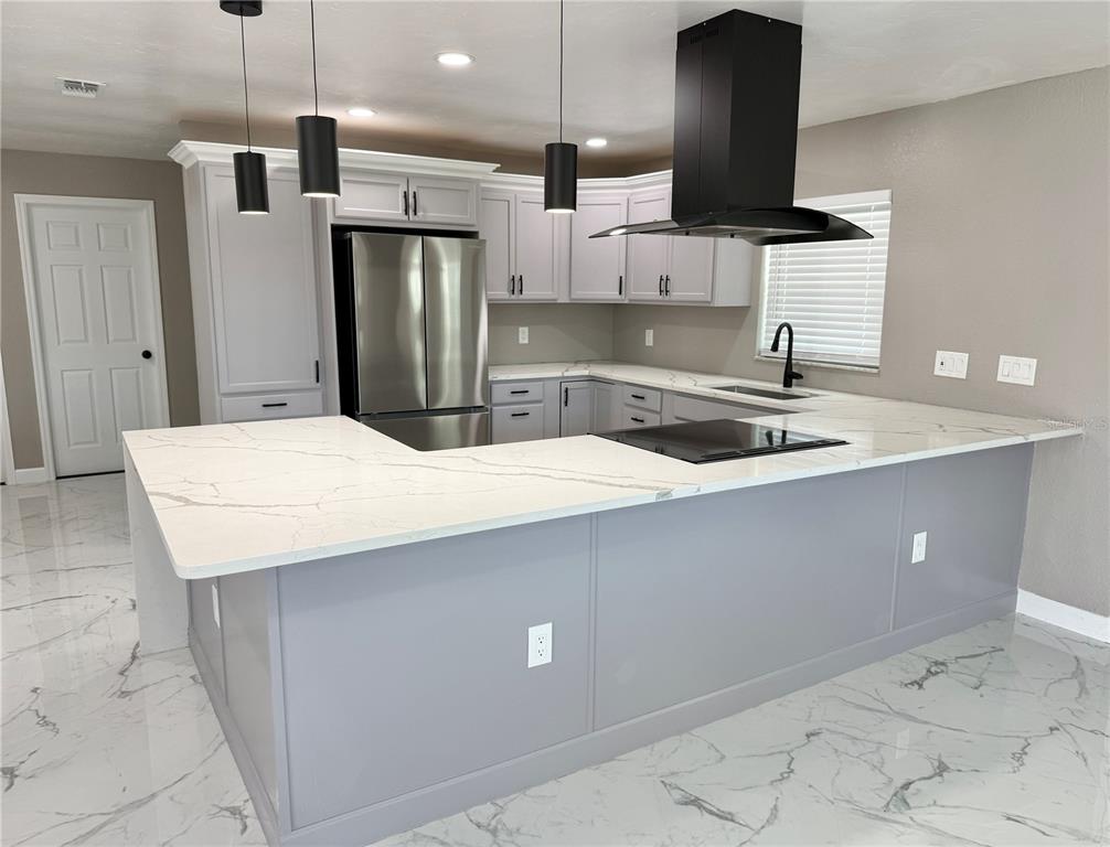 A modern kitchen features light gray cabinets, white marble-patterned countertops, and a black range hood — 715 65TH AVENUE DRIVE W, BRADENTON, FL