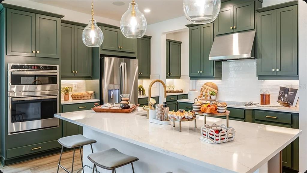 A modern kitchen features green cabinets, a white quartz island, and stainless steel appliances — 5790 BINNACLE LANE, COCOA, FL