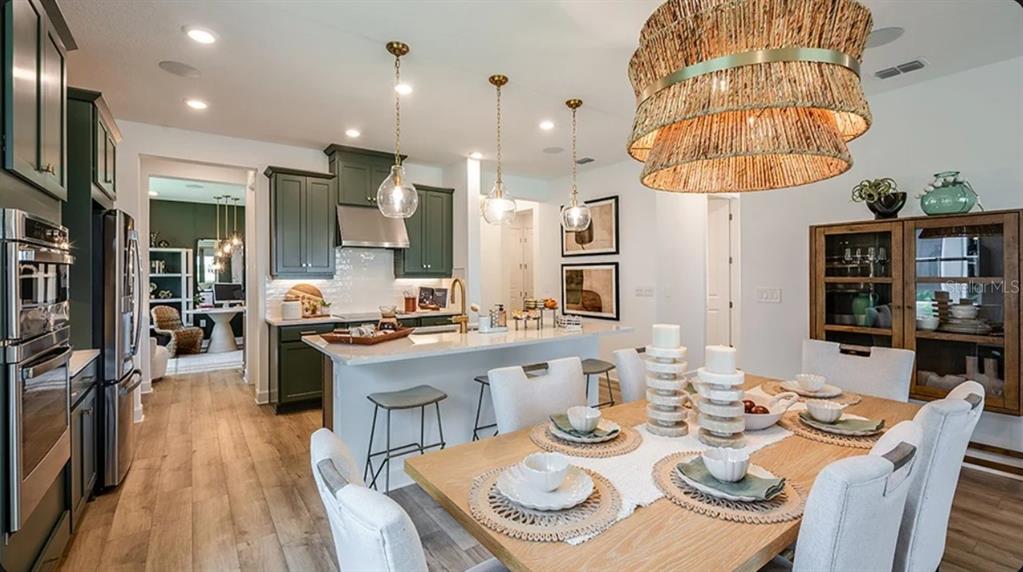 A kitchen and dining area with dark green cabinets, a large island, and wood flooring — 5790 BINNACLE LANE, COCOA, FL