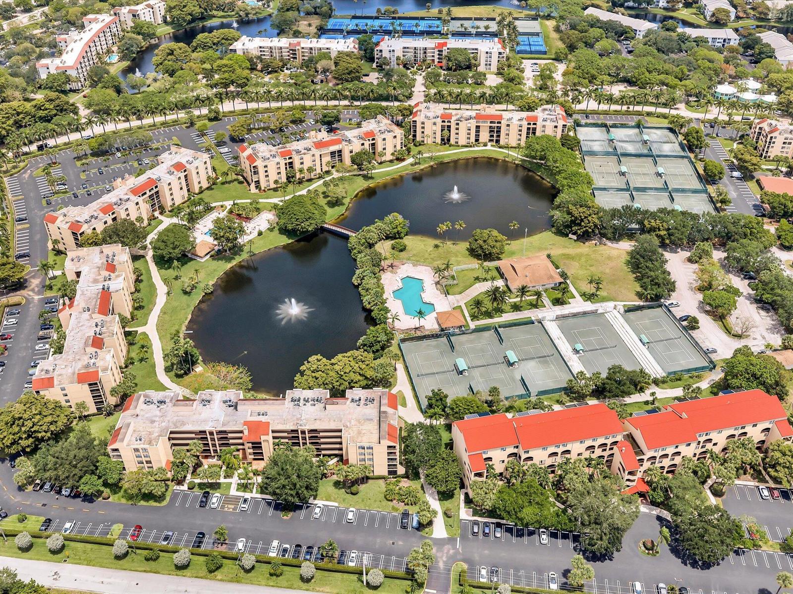 An aerial view shows apartment buildings surrounding two ponds with fountains, tennis courts, and pools — 2455 Lindell Boulevard # 3401, Delray Beach FL 33444, DELRAY BEACH, FL