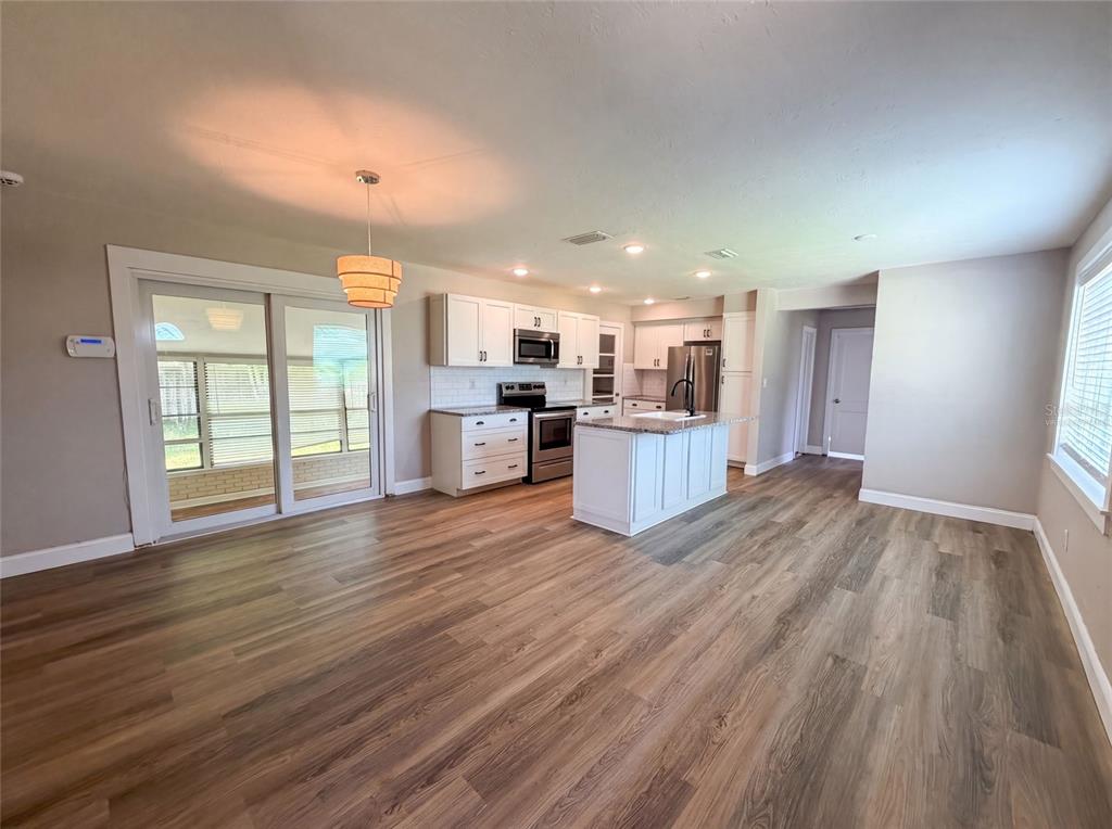 A kitchen features a granite-topped island, white cabinetry, stainless steel appliances, and wood-look flooring — 1521 W RIVER SHORE WAY, TAMPA, FL