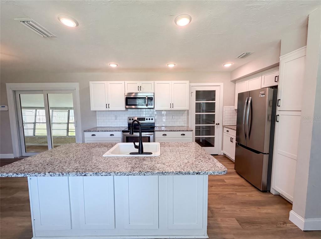 A bedroom with light gray paneled walls, wood-look flooring, a ceiling fan, and sliding closet doors — 1521 W RIVER SHORE WAY, TAMPA, FL