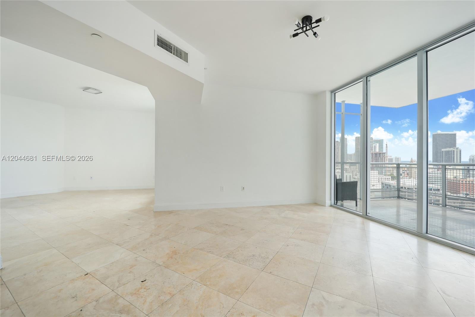 An empty room with light tile floors, white walls, and a balcony overlooking a city — 350 S Miami Ave # 2411, Miami FL 33130, MIAMI, FL