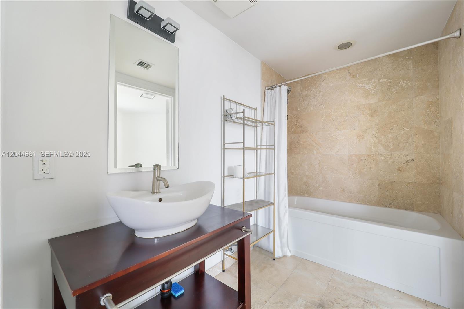 A bathroom features a vessel sink on a dark wood vanity and a tiled bathtub — 350 S Miami Ave # 2411, Miami FL 33130, MIAMI, FL