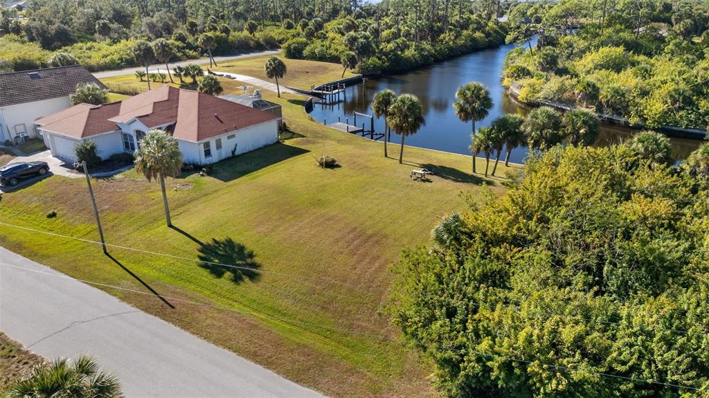 An aerial view shows a house with a red roof next to a grassy lot — 1387 GLANMORE DRIVE, PORT CHARLOTTE, FL