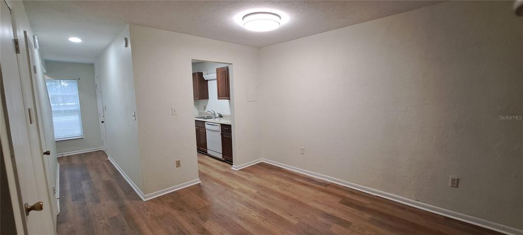 A room with wood-look flooring leads to a kitchen with dark cabinets and white appliances — 3925 SW 26TH TERRACE UNIT B, GAINESVILLE, FL