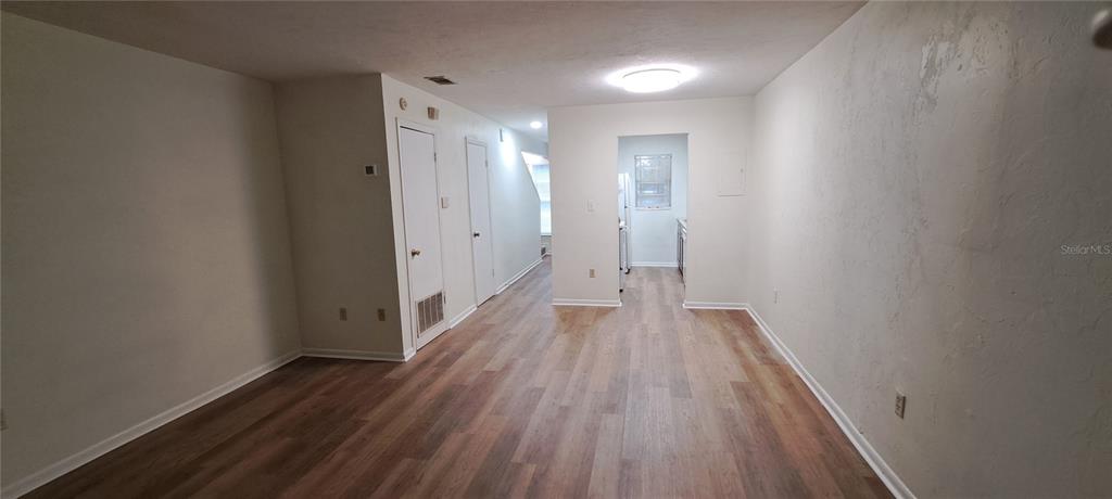 A living area with light wood-look flooring leads to a kitchen through a central doorway — 3925 SW 26TH TERRACE UNIT B, GAINESVILLE, FL