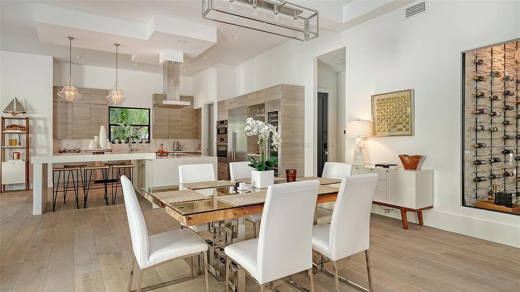 A modern dining area with a glass table and white chairs adjacent to a kitchen — 1421 N LAKE SHORE DRIVE, SARASOTA, FL