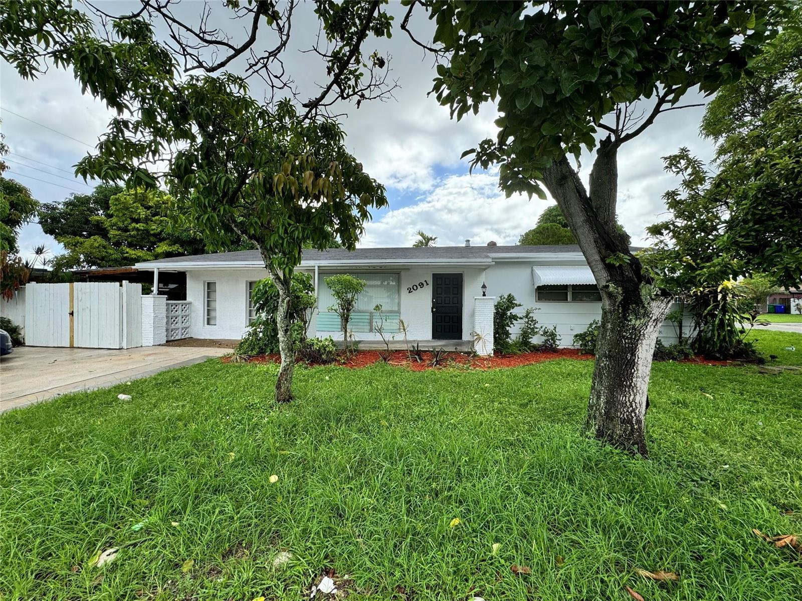 A white single-story house with a black front door and a large front lawn — 2091 Oleander Drive, Miramar FL 33023, MIRAMAR, FL