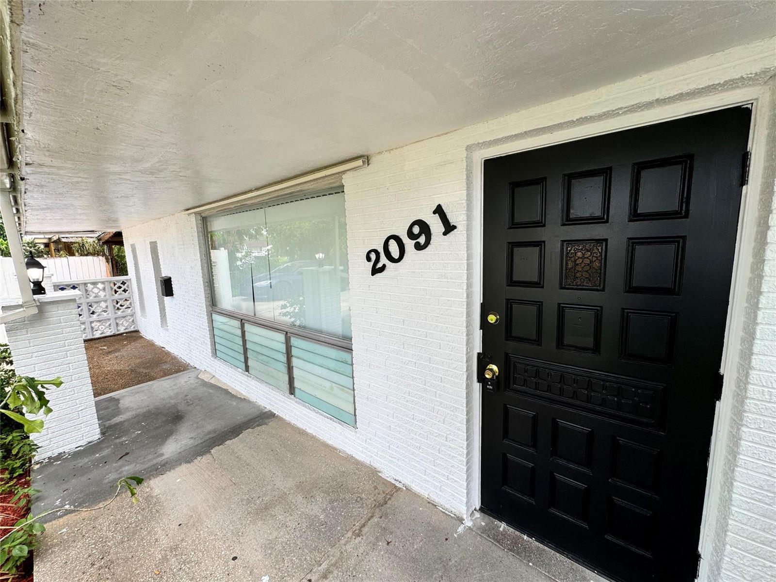 A white brick exterior features a black front door and the house number 2091 — 2091 Oleander Drive, Miramar FL 33023, MIRAMAR, FL