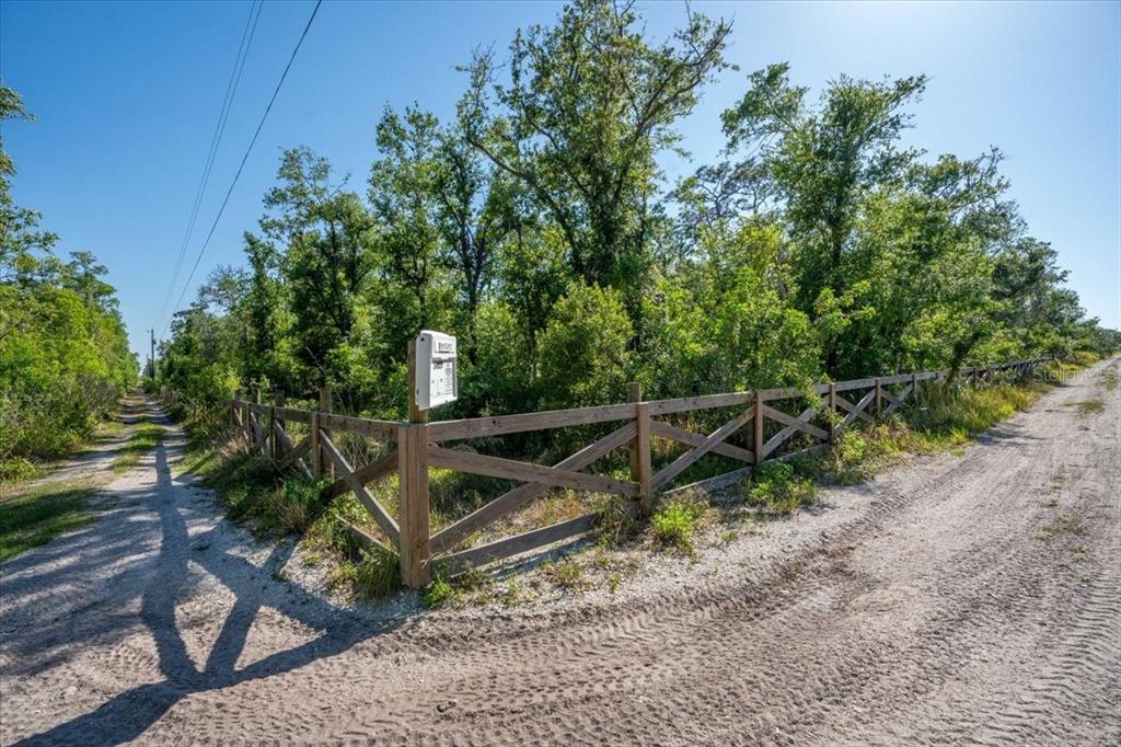 A wooden fence encloses a wooded lot at the intersection of two dirt roads — 24820 49TH AVENUE E, MYAKKA CITY, FL