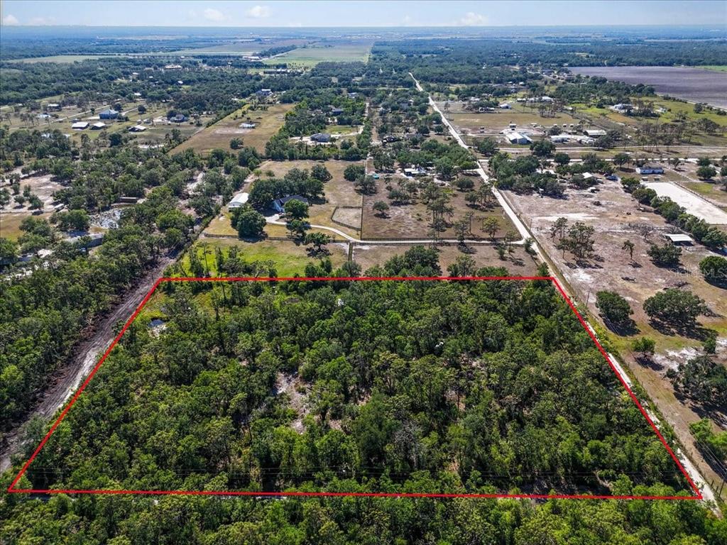 An aerial view shows a rectangular, tree-covered plot of land outlined in red — 24820 49TH AVENUE E, MYAKKA CITY, FL