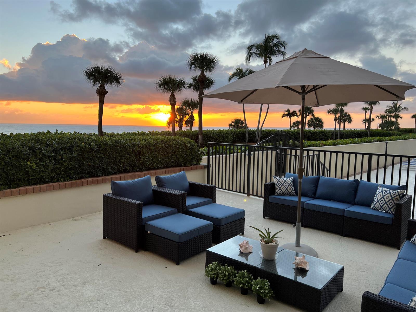 A patio features outdoor furniture, a large umbrella, and a sunset view over the ocean — 400 Ocean Trail Way # 101, Jupiter FL 33477, JUPITER, FL