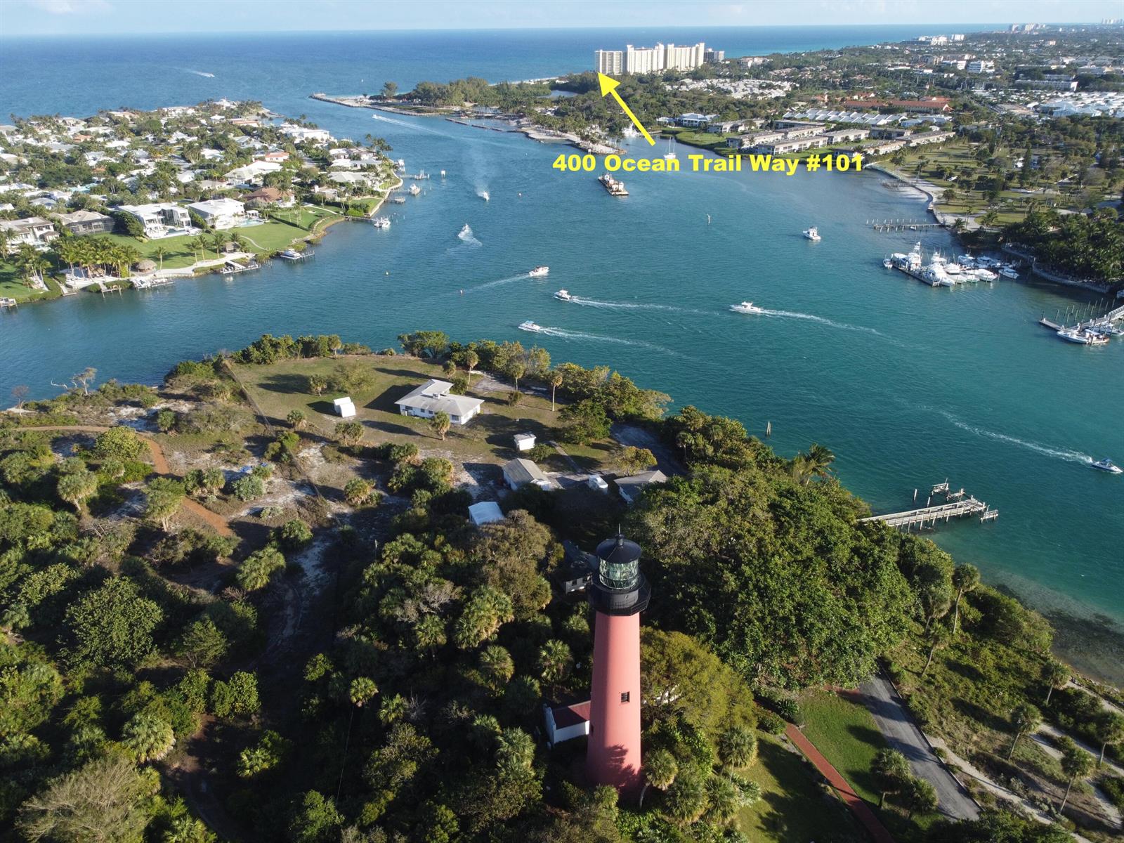 An aerial view shows a lighthouse in the foreground overlooking a waterway with boats — 400 Ocean Trail Way # 101, Jupiter FL 33477, JUPITER, FL