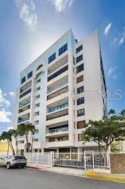 A multi-story white residential building with balconies and a gated parking area at street level — Cond Esmeralda #7 CALLE AMAPOLA UNIT 602, CAROLINA, PR