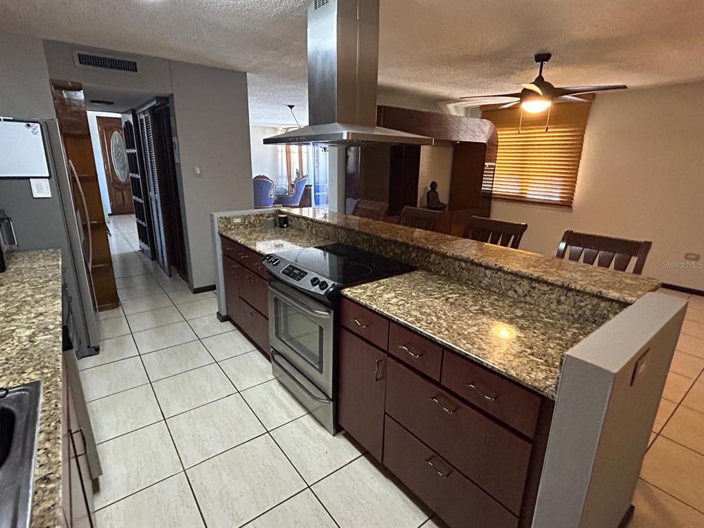 A kitchen with granite countertops, dark wood cabinets, and a stainless steel range hood — Cond Esmeralda #7 CALLE AMAPOLA UNIT 602, CAROLINA, PR