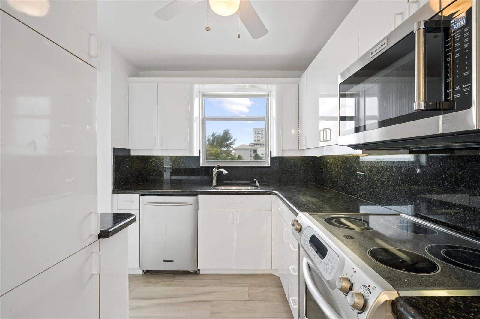 A kitchen with white cabinets, black granite countertops, stainless steel appliances, and a window view — 1010 S Ocean Boulevard # 501, Pompano Beach FL 33062, POMPANO BEACH, FL