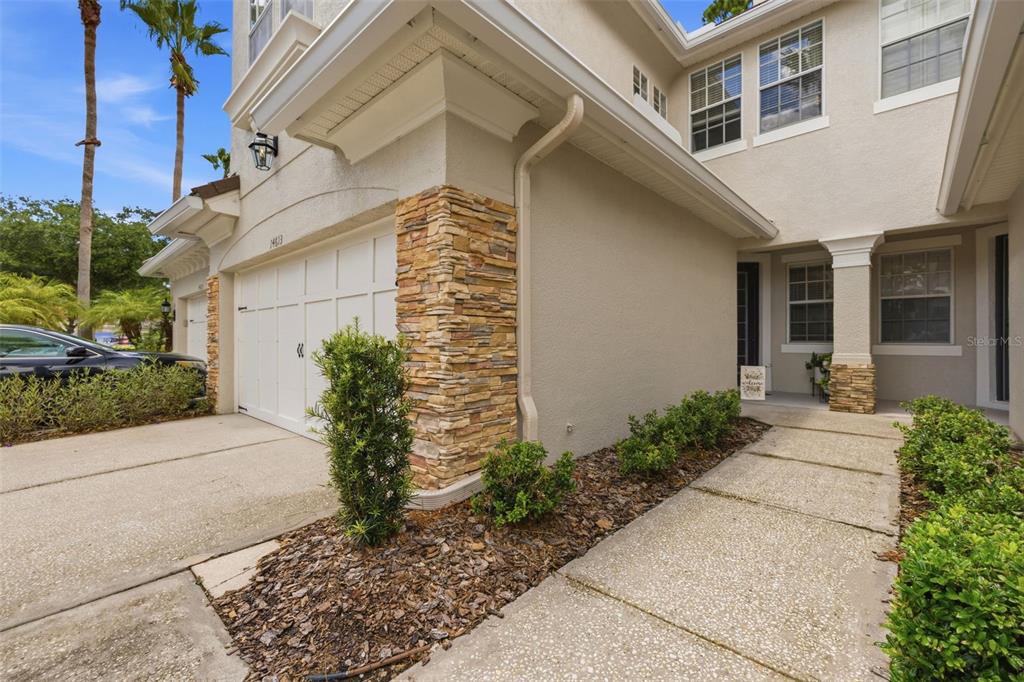 A two-story house exterior features a stone-accented garage, a concrete driveway, and a front walkway — 14613 MIRABELLE VISTA CIRCLE, TAMPA, FL