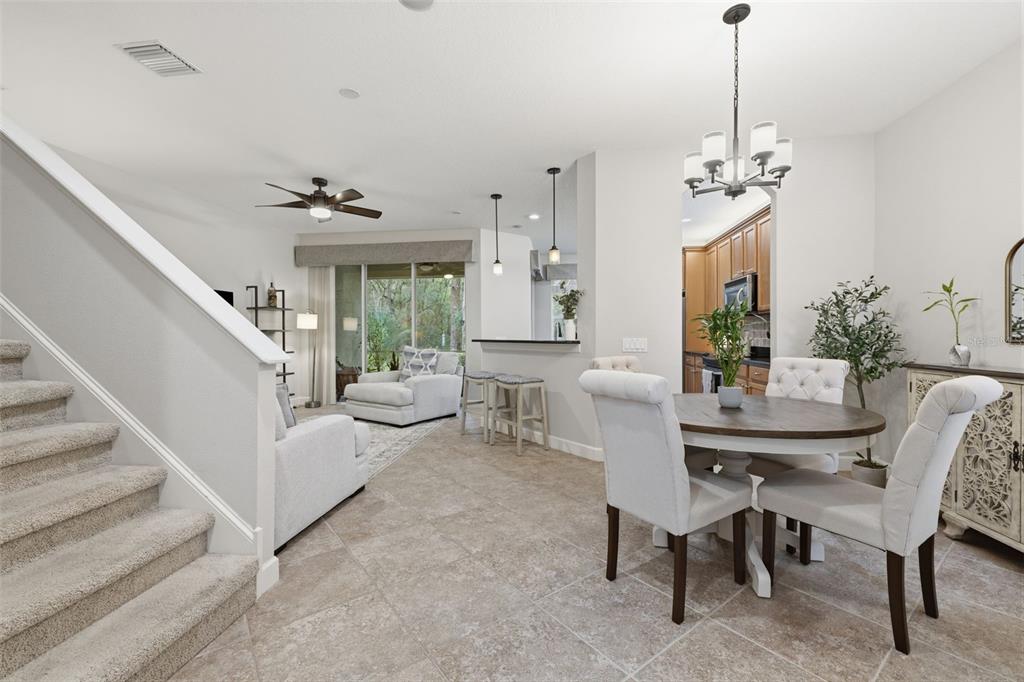 An open-concept living and dining area features tile flooring, a staircase, and a kitchen pass-through — 14613 MIRABELLE VISTA CIRCLE, TAMPA, FL