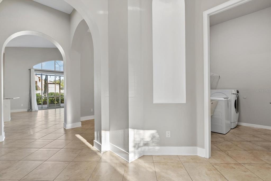 A tiled hallway leads to a laundry room and an open living area with patio access — 6634 38TH STREET E, SARASOTA, FL
