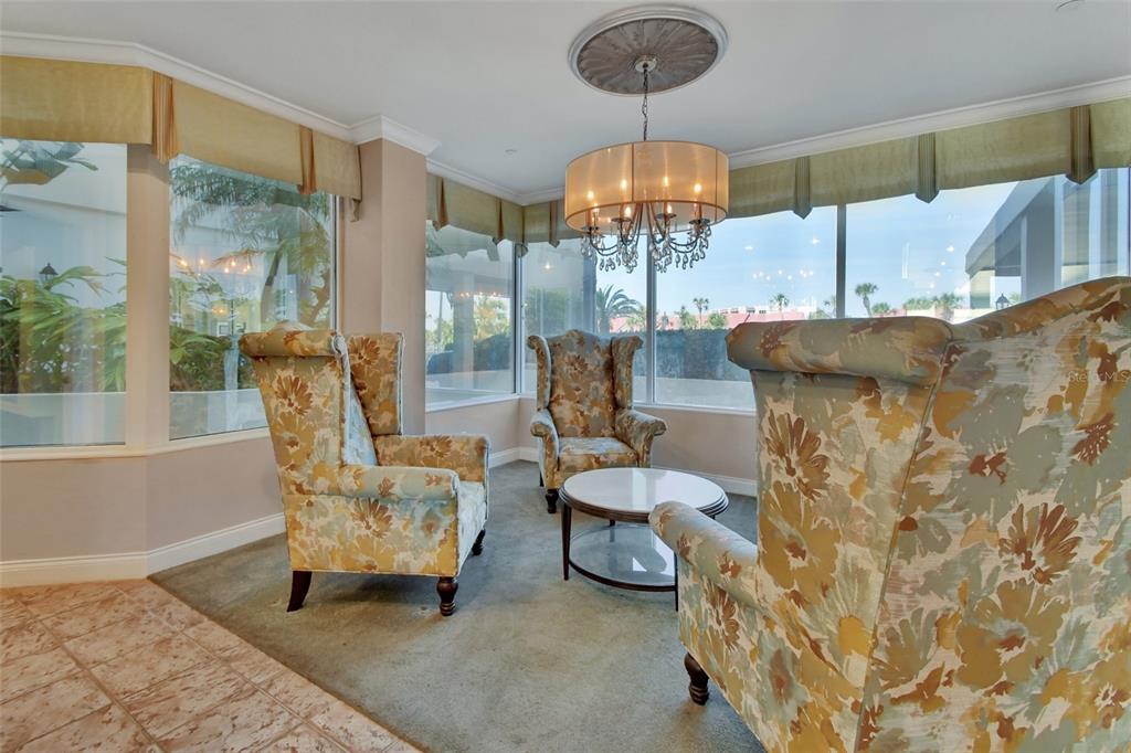 A sunroom features three floral wingback chairs, a glass-topped coffee table, and large windows — 2937 S ATLANTIC AVENUE UNIT 708, DAYTONA BEACH SHORES, FL