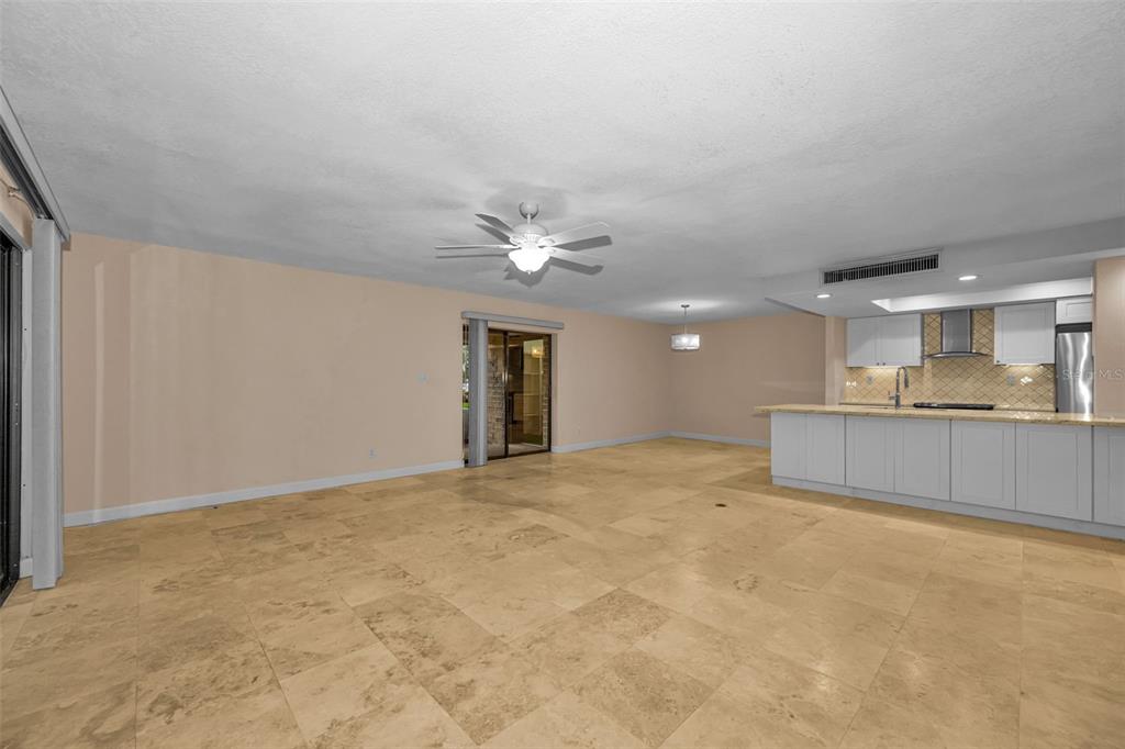 An open-concept living area features light-colored tile flooring, a ceiling fan, and a kitchen island — 36750 US HIGHWAY 19 UNIT 26-102, PALM HARBOR, FL