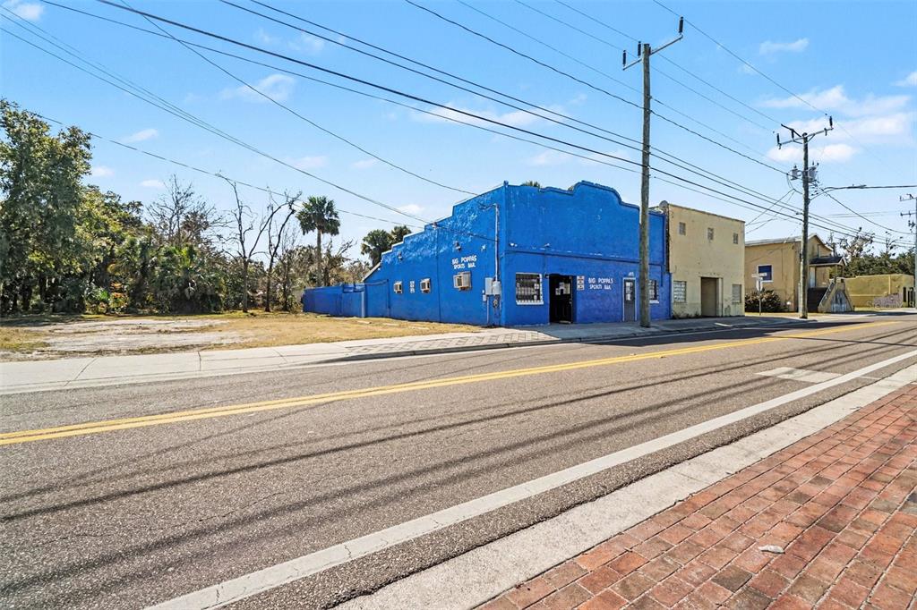 A blue, two-story commercial building stands next to a vacant lot along a paved road — 1013 HISTORIC GOLDSBORO BOULEVARD, SANFORD, FL