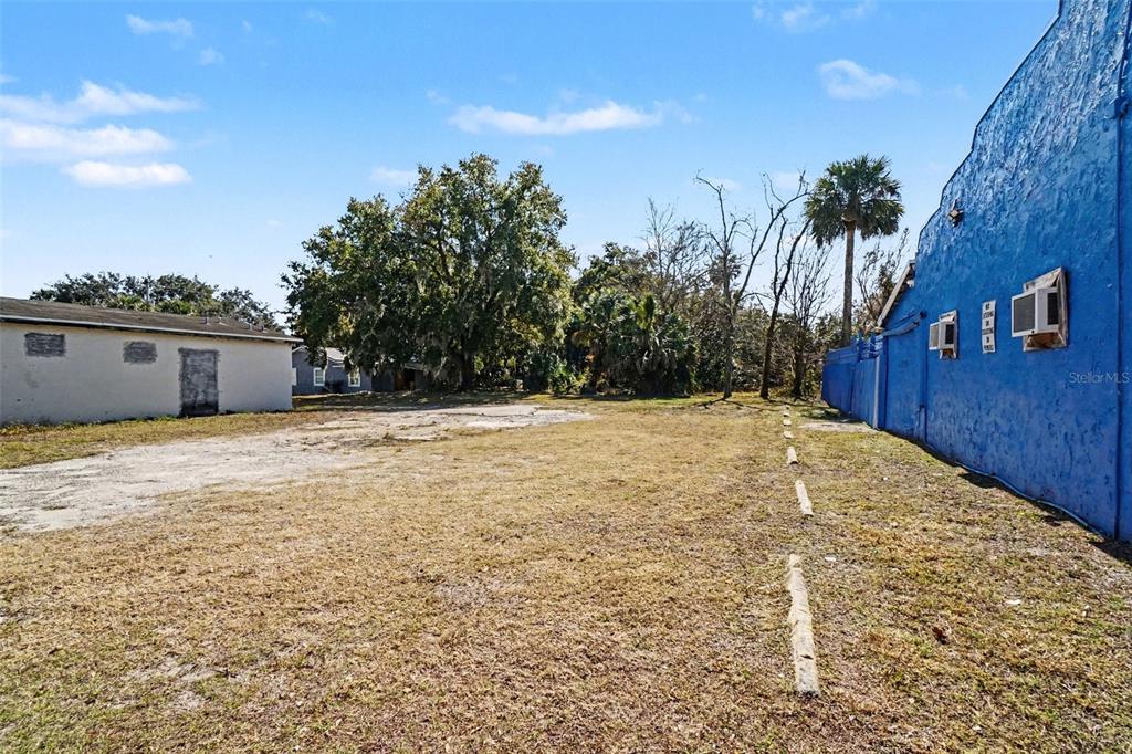A vacant lot sits between a small white building and a large blue wall — 1013 HISTORIC GOLDSBORO BOULEVARD, SANFORD, FL