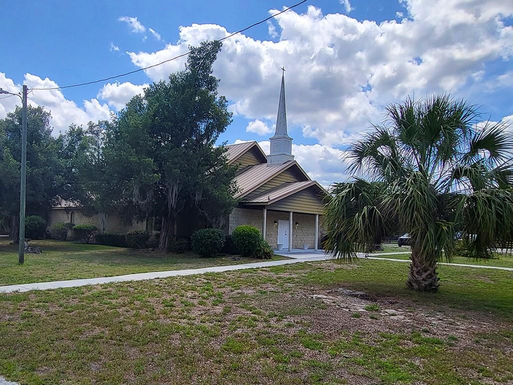 A church building with a steeple stands on a grassy lot with a palm tree — 1990 SE HIGHWAY 42 UNIT 1, SUMMERFIELD, FL