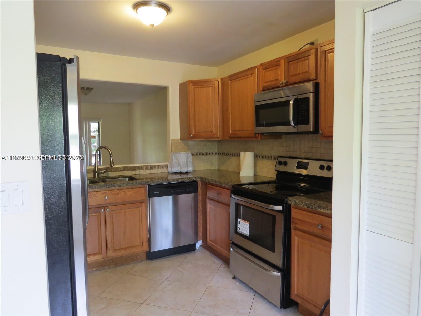 A kitchen features wood cabinets, stainless steel appliances, and granite countertops — 216 Lakeside Cir, Sunrise FL 33326, SUNRISE, FL