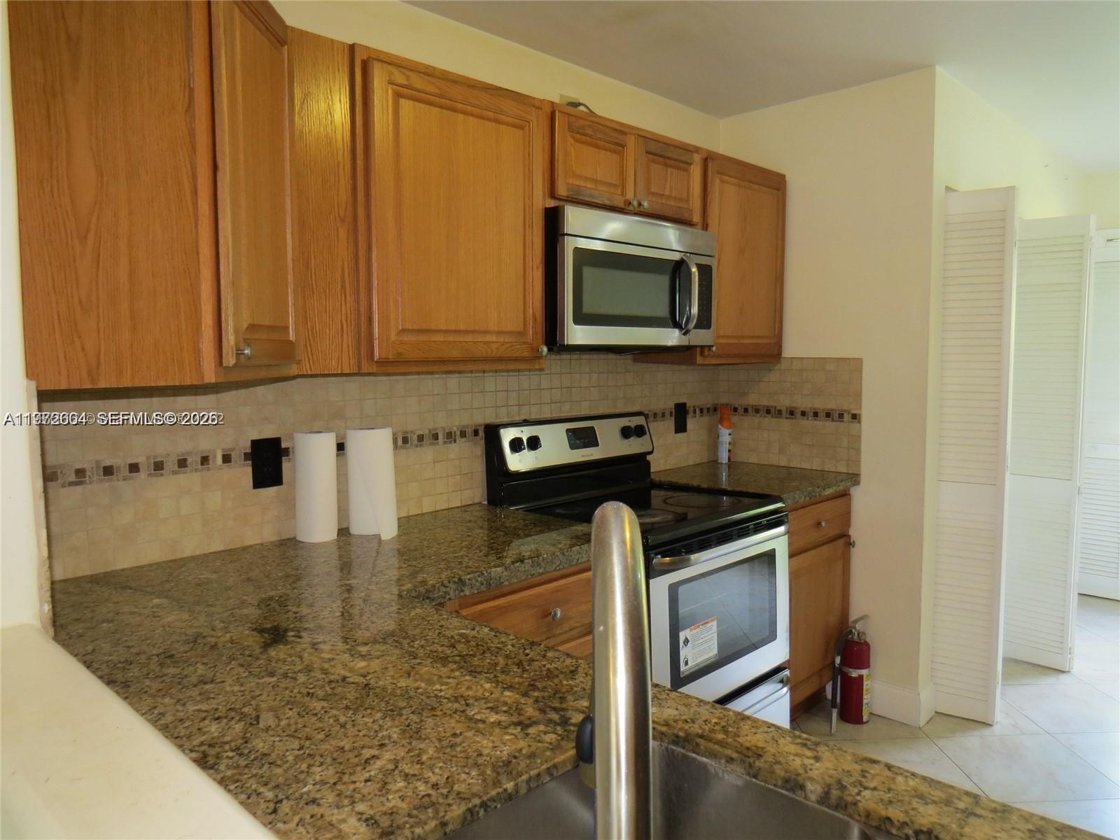 A kitchen features wood cabinets, granite countertops, a stainless steel microwave, and a range — 216 Lakeside Cir, Sunrise FL 33326, SUNRISE, FL