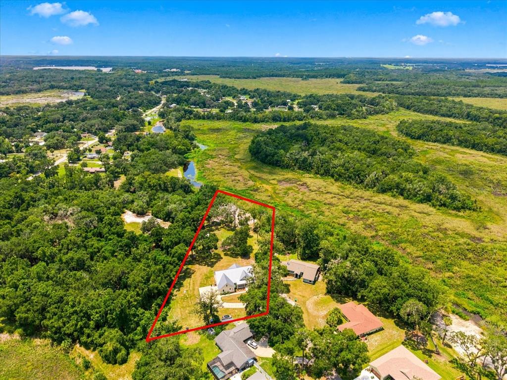 An aerial view shows a house with a red outline on a large, wooded lot — 32 N SHADOW WOOD DRIVE, INVERNESS, FL