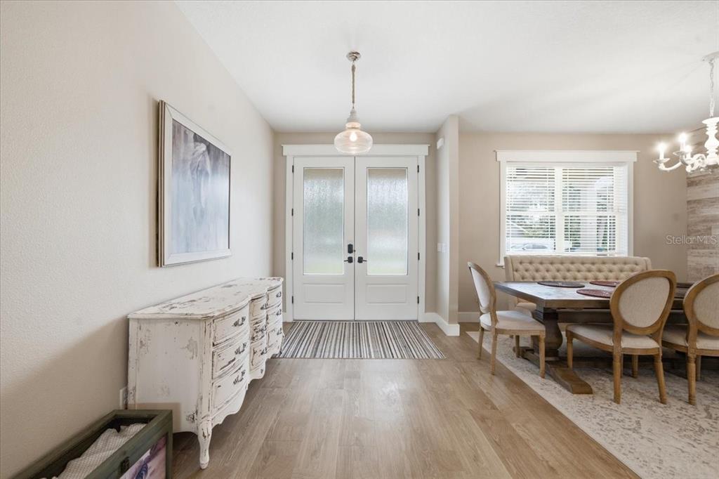 An entryway features a distressed white cabinet, a striped rug, and a dining area nearby — 32 N SHADOW WOOD DRIVE, INVERNESS, FL