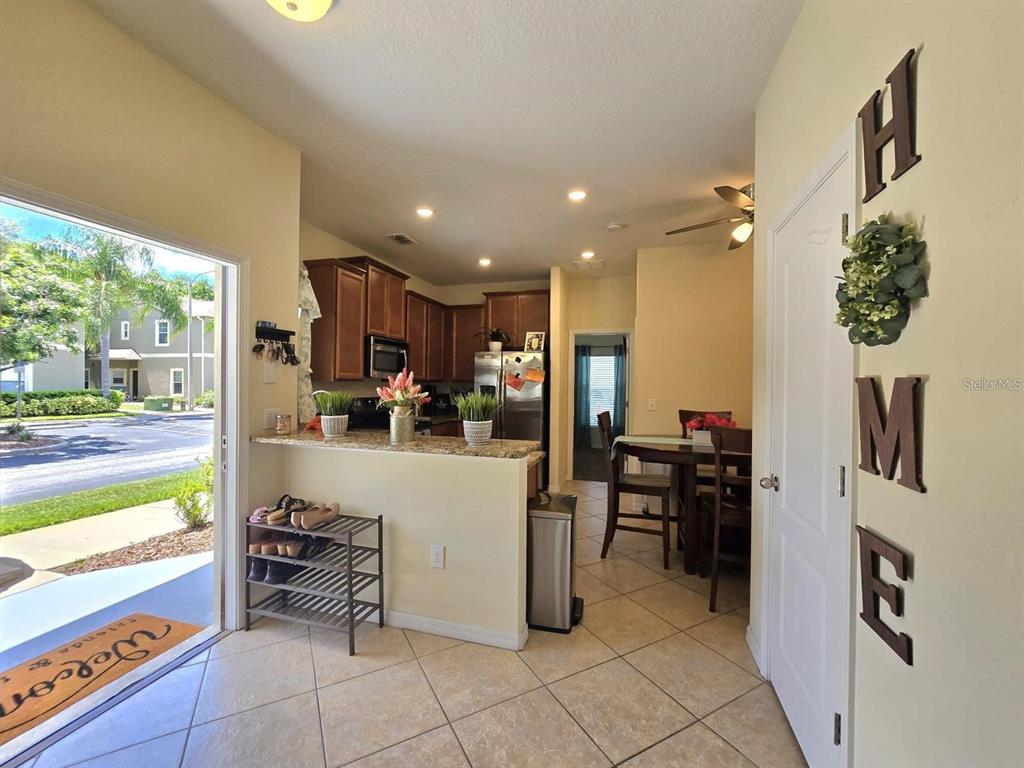 An open-concept kitchen with wood cabinets and a breakfast bar overlooks a dining area — 31142 GOSSAMER WAY, WESLEY CHAPEL, FL