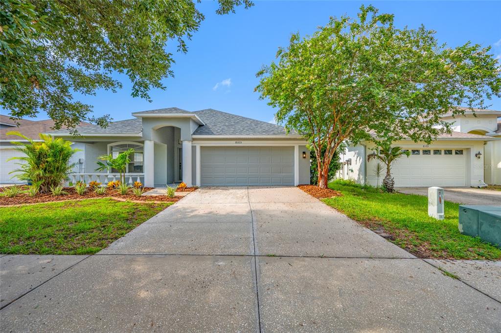 A single-story house with a gray garage, a concrete driveway, and a landscaped front yard — 8105 WATER TOWER DRIVE, TAMPA, FL