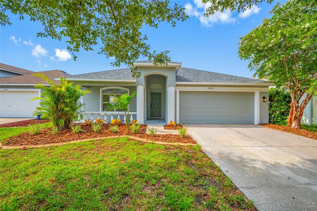 A single-story house with a gray garage, a front porch, and a landscaped yard — 8105 WATER TOWER DRIVE, TAMPA, FL
