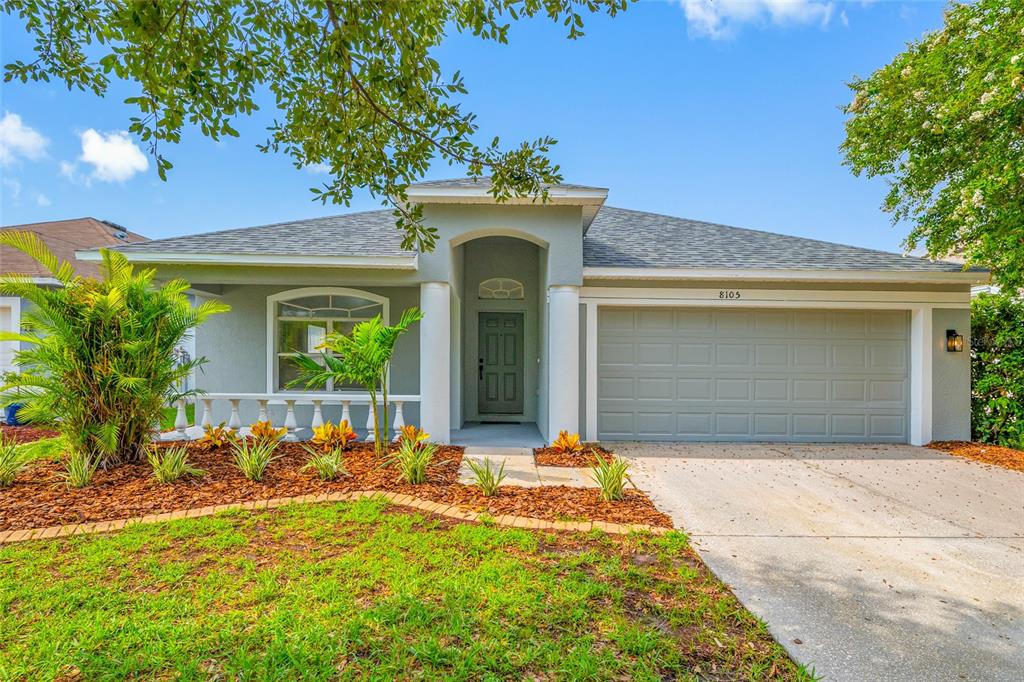 A single-story house with a gray exterior, a two-car garage, and a landscaped front yard — 8105 WATER TOWER DRIVE, TAMPA, FL