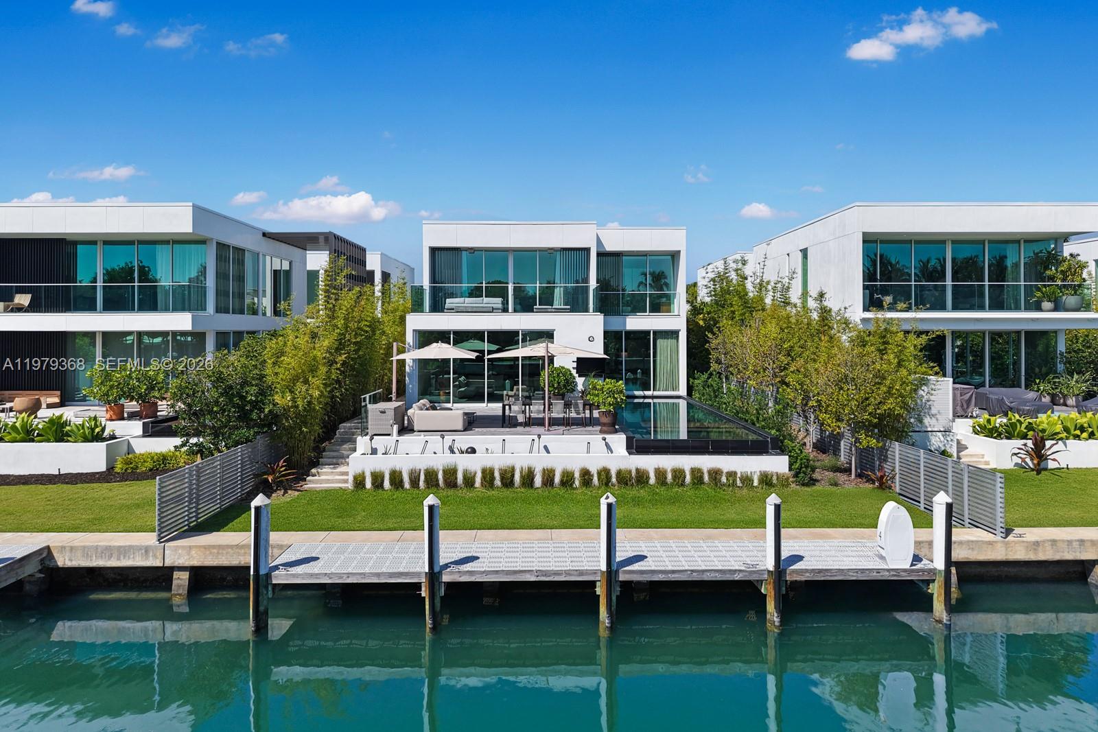 An exterior view of a modern waterfront home with a pool, patio, and private dock — 1051 W 48th St # 4, Miami Beach FL 33140, MIAMI BEACH, FL