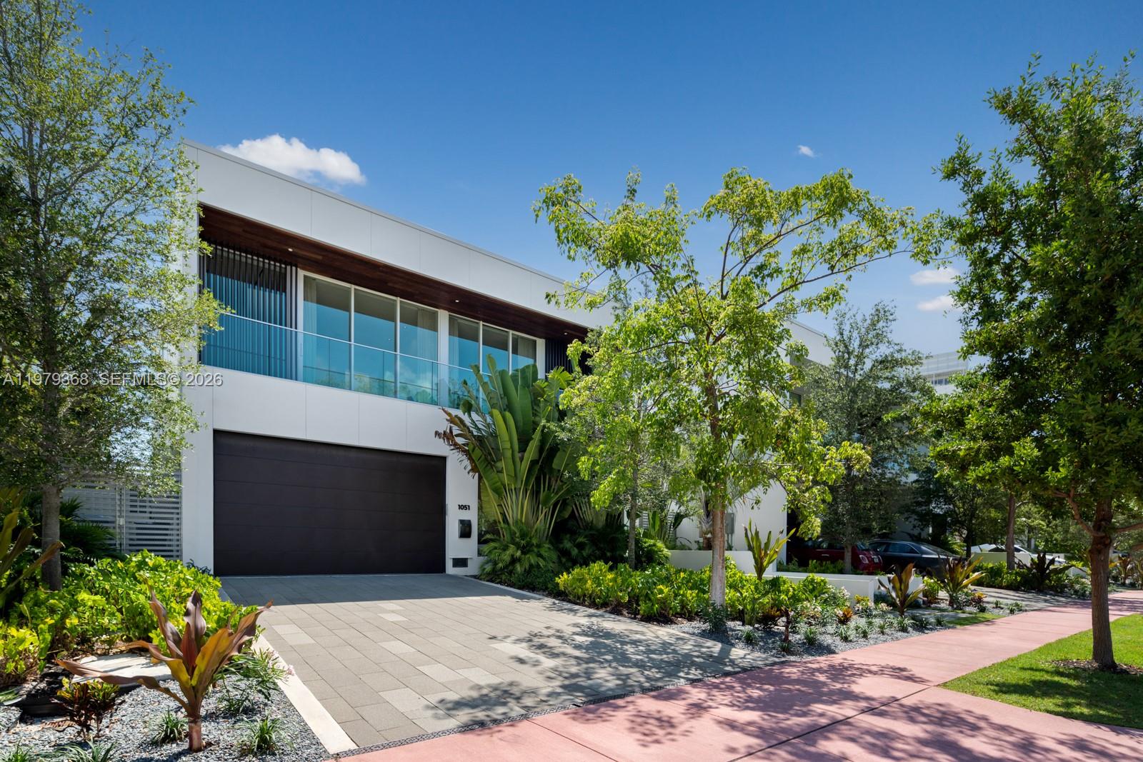 A modern two-story house with a white facade, dark garage door, and glass balcony — 1051 W 48th St # 4, Miami Beach FL 33140, MIAMI BEACH, FL
