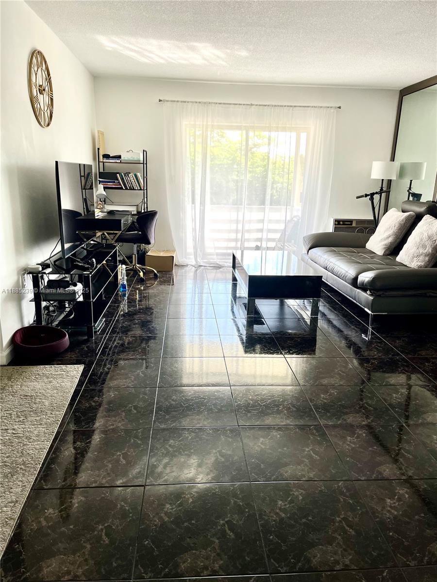 A living room features dark marble-style tile flooring, a grey sofa, and a glass coffee table — 1395 NE 167th St # 315, Miami FL 33162, MIAMI, FL