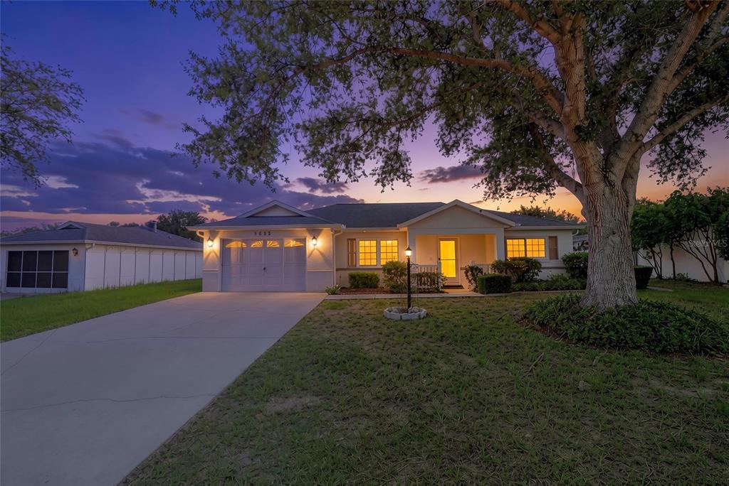 A single-story house with a garage and a large tree in the front yard at dusk — 9685 SW 97TH STREET, OCALA, FL