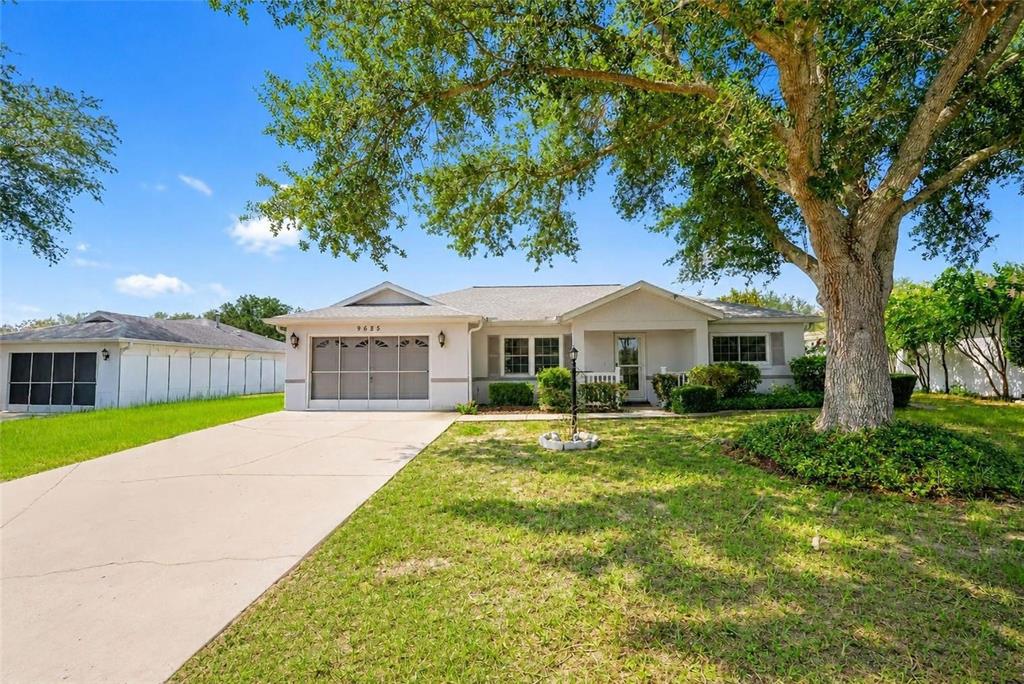 A single-story house with a concrete driveway, a garage, and a large tree in front — 9685 SW 97TH STREET, OCALA, FL