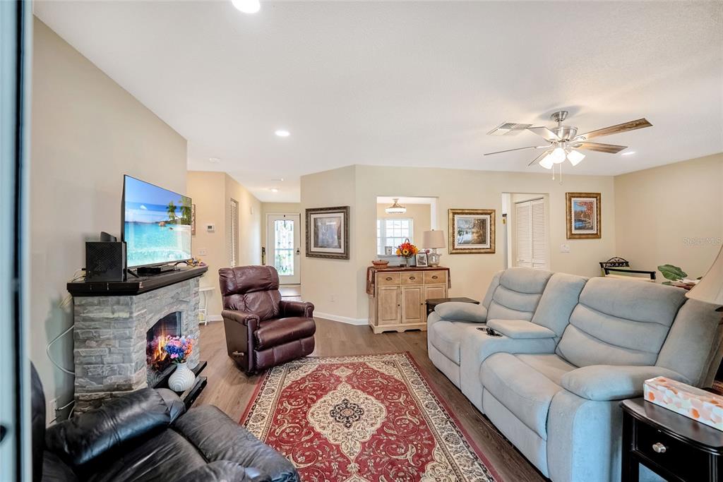 A living room features a stone fireplace, a leather recliner, and a light-colored sofa — 9685 SW 97TH STREET, OCALA, FL